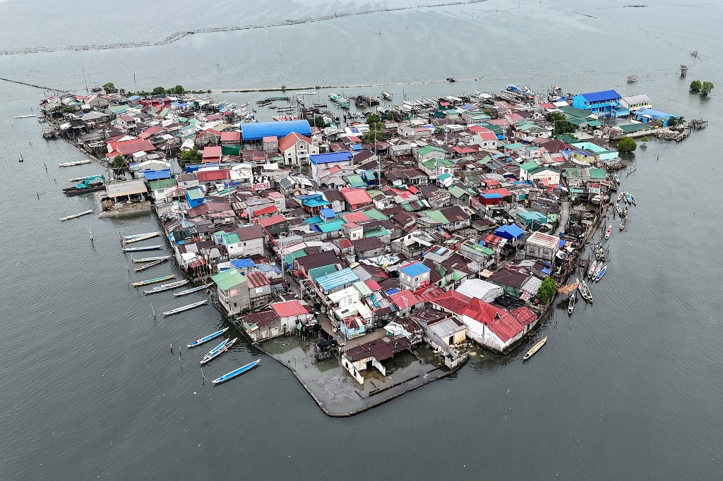 This aerial view taken on July 7, 2025, shows cramped houses on Isla Pugad in Hagonoy town, Bulacan province, north of Manila. Sea levels across the Philippines as a whole are rising three times faster than the global average of 3.6 millimeters per year, and the Department of Environment and Natural Resources (DENR) has said this could accelerate to 13 millimeters annually.