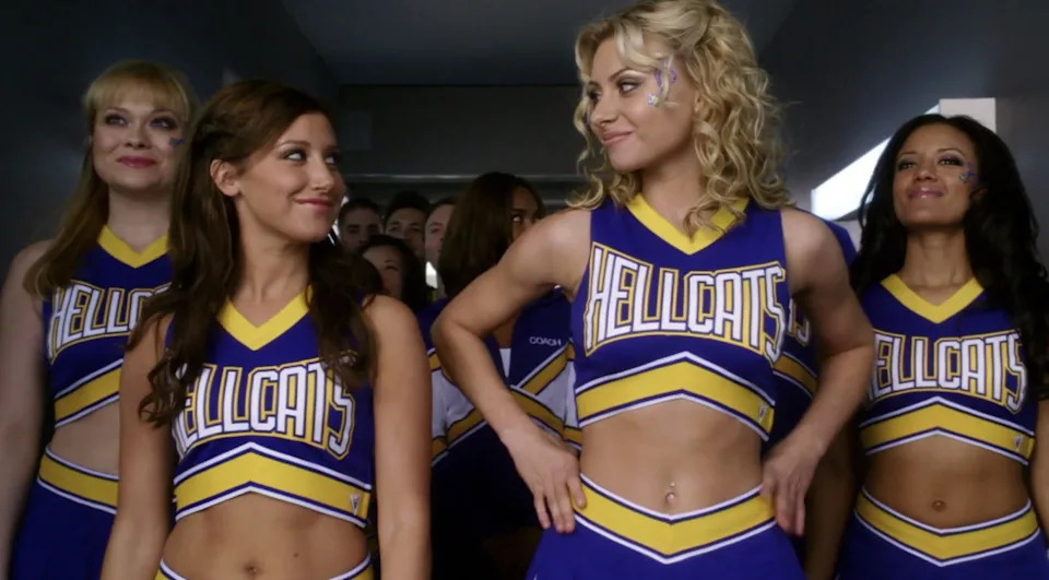 Group of cheerleaders in matching uniforms confidently walking forward in a hallway