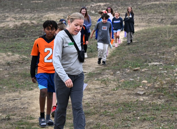 Volunteer Renee Jacobsen leads a group of Heatherwood Elementary fourth graders to a rock formation during a Sept. 5 field trip. (Photo by Cliff Grassmick/Staff Photographer)
