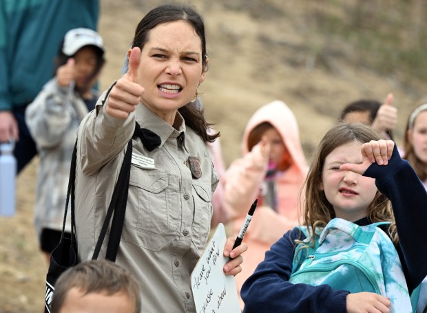 Maggie Vest Engelman, left, of Boulder Open Space and Mountain Parks, shows Heatherwood fourth graders students the thumb trick to judge how far they should be from an animal. (Cliff Grassmick/Staff Photographer)