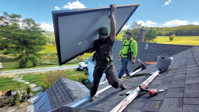 Devin Perkins (left) and Collin Ash of Catamount Solar installing panels on a home in North Pomfret
