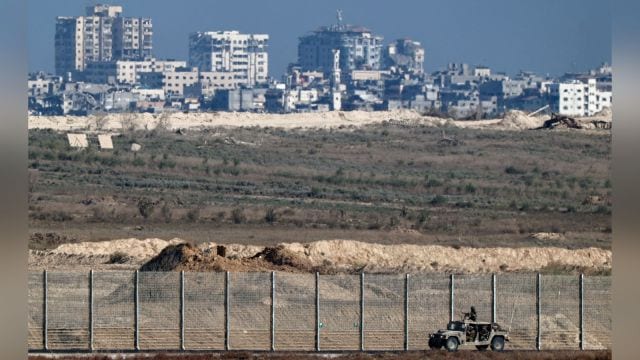 An Israeli military vehicle drives next to the Israel-Gaza border as Gaza City is seen in the distance. (Reuters Photo)