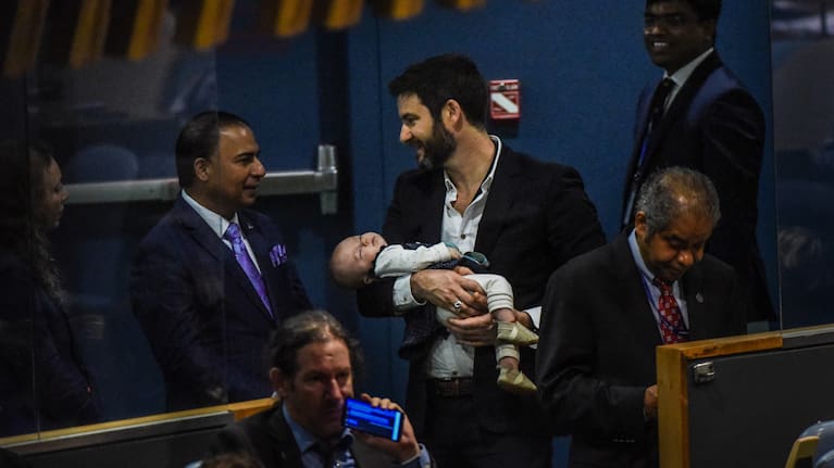 Clarke Gayford holding the baby while Jacinda Ardern delivers a speech at the United Nations headquarters in New York, in 2018.