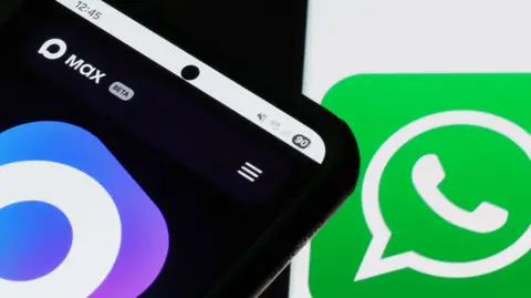 Getty Images Photograph of a smartphone displaying the logo of the Russian messaging app Max on its screen, with the WhatsApp logo visible in the background.