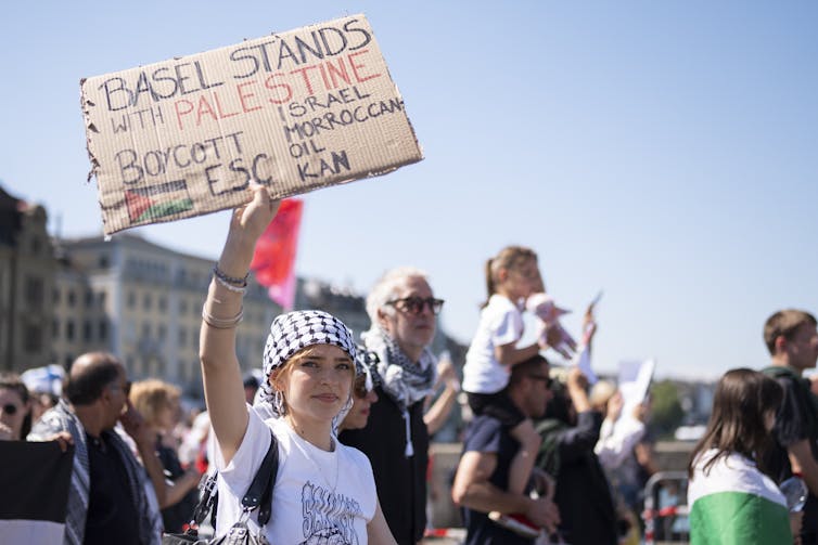 A demonstrator holds a placard reading 'Basel stands with Palestine'