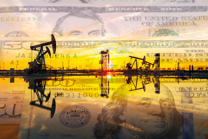 Oil pumps at sunrise with money in the background.