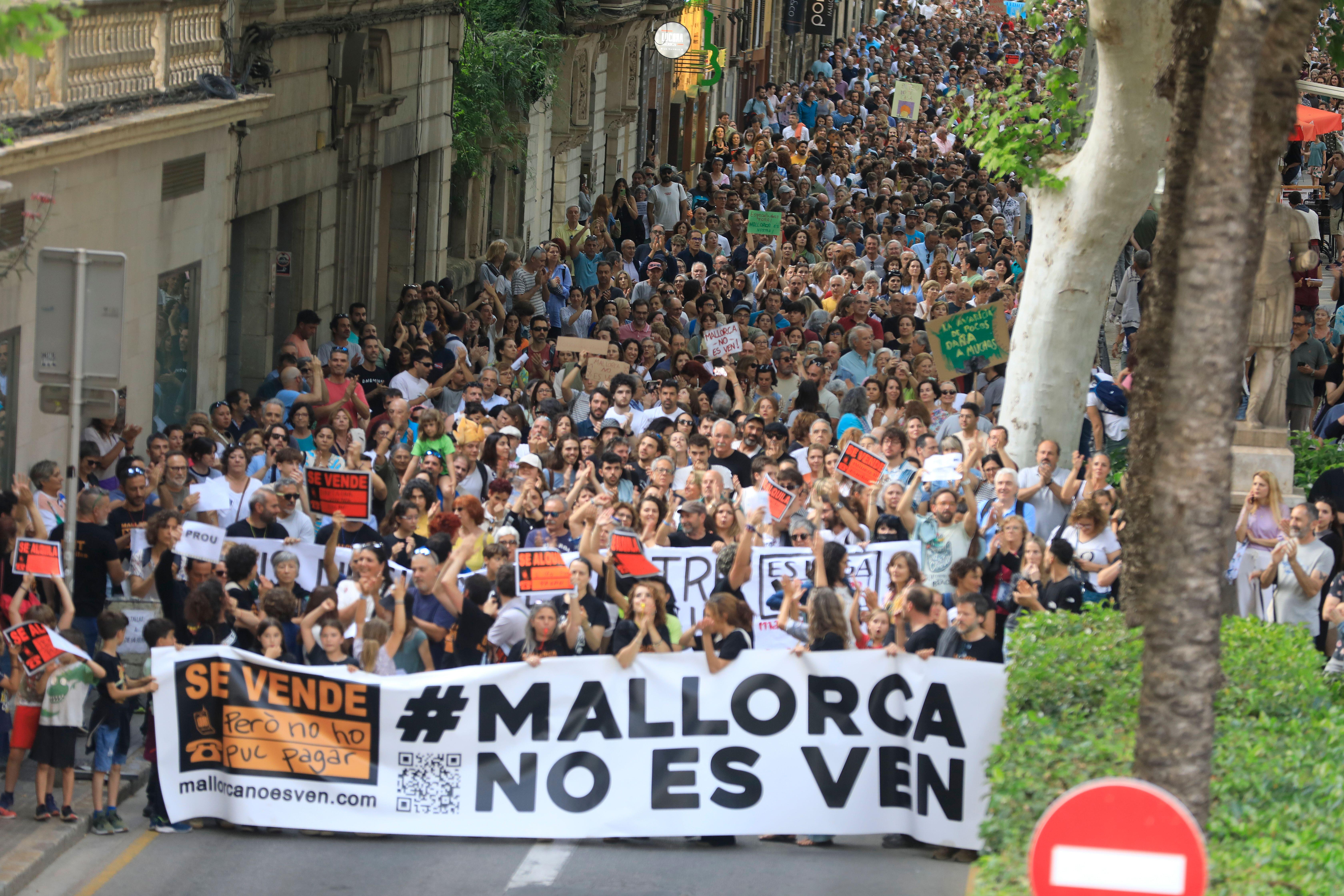 Thousands of locals demonstrate against mass tourism in Palma, Spain, holding signs and a banner that reads "#Mallorca No Es Ven" (Mallorca is not for sale).