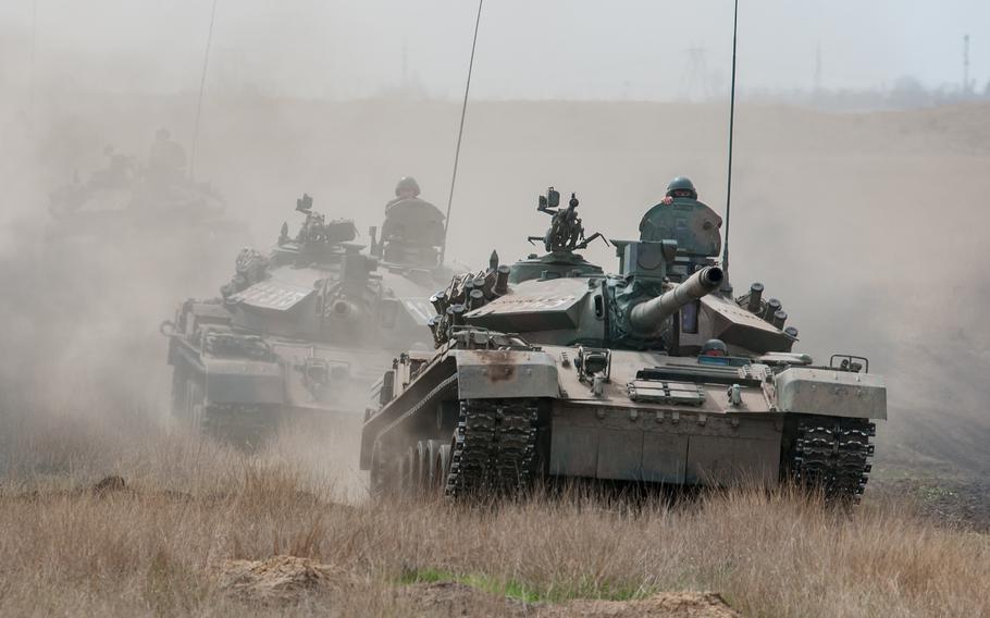 Two tanks maneuver in a live-fire exercise.