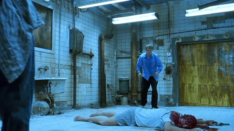 Lawrence looking at a dead body in a torture bathroom in Saw
