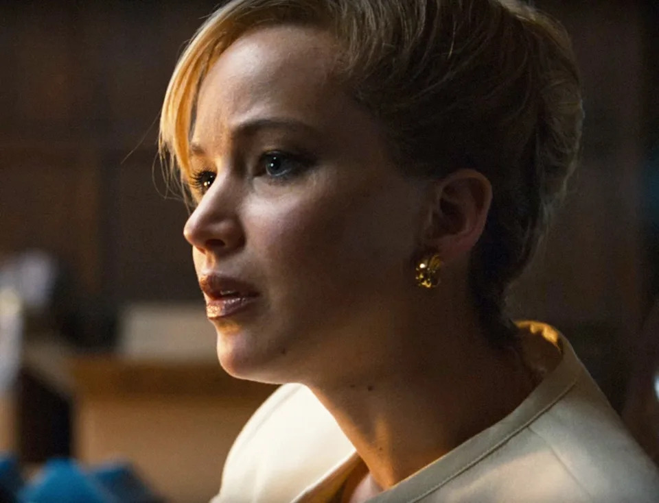 Side profile image of Jennifer Lawrence wearing a white jacket and her hair is pinned up