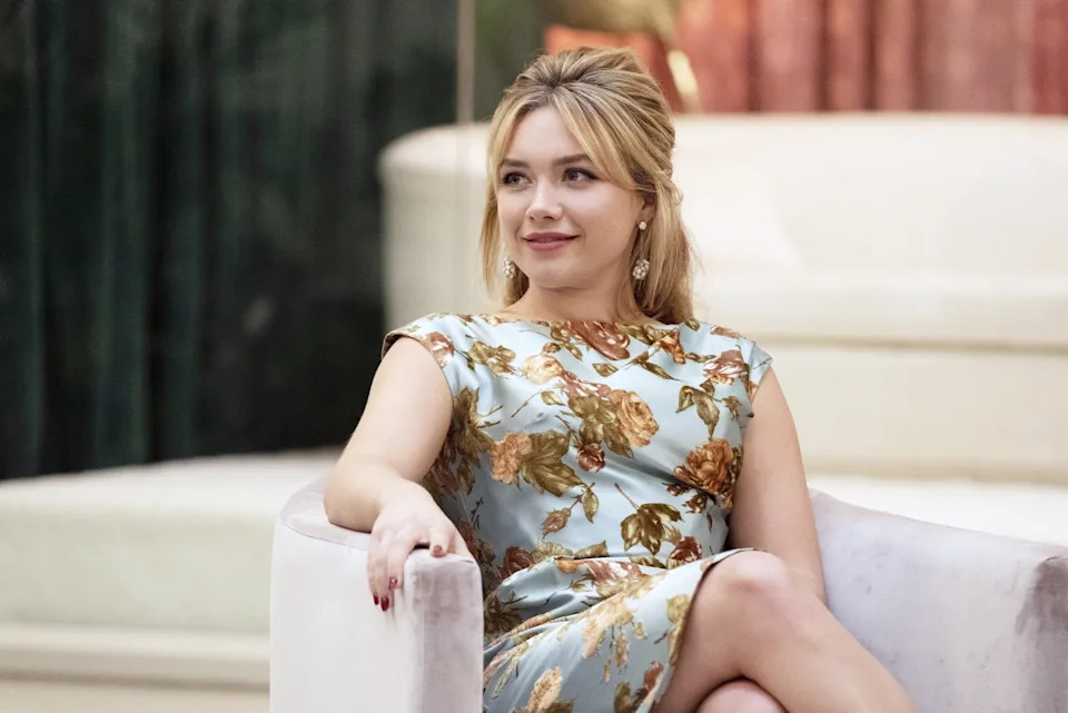 Florence Pugh in a floral gown, sitting on a velvet chair