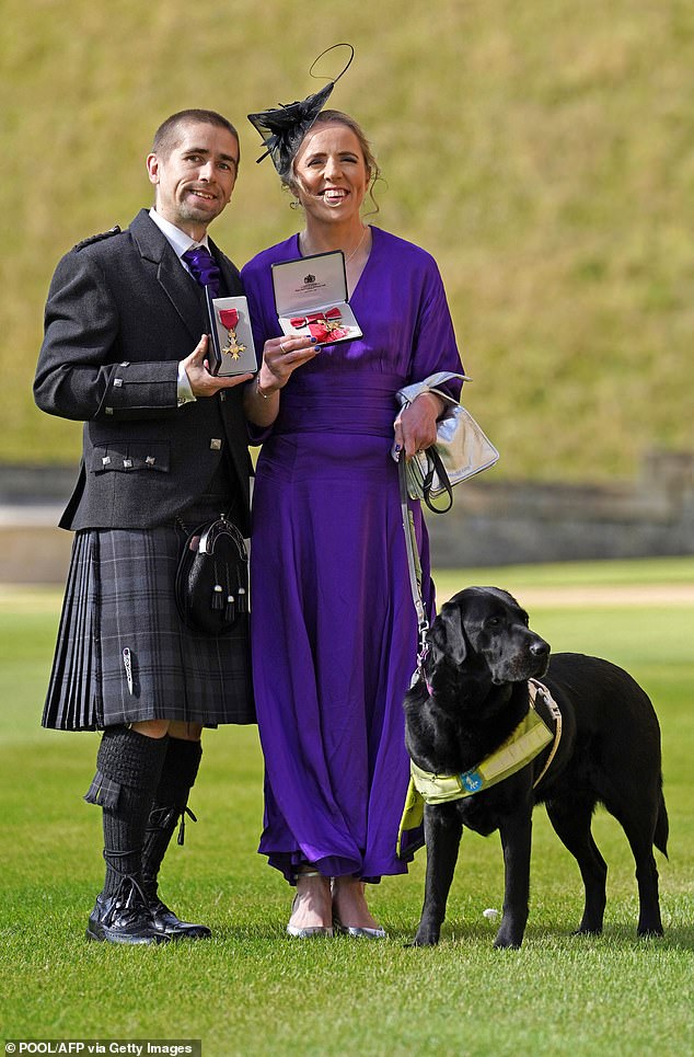 Neil and Lora Fachie pose with their medals after they were both awarded OBEs in 2023