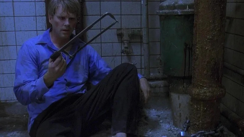 Lawrence holding a saw in Saw