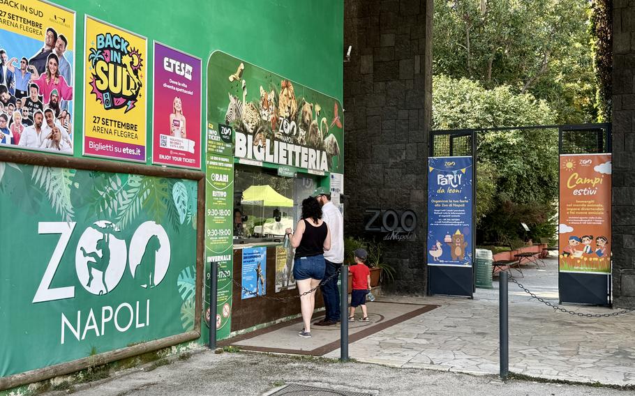 The entrance to Zoo Napoli (Naples Zoo) with a large green sign displaying the zoo’s logo and promotional posters. 