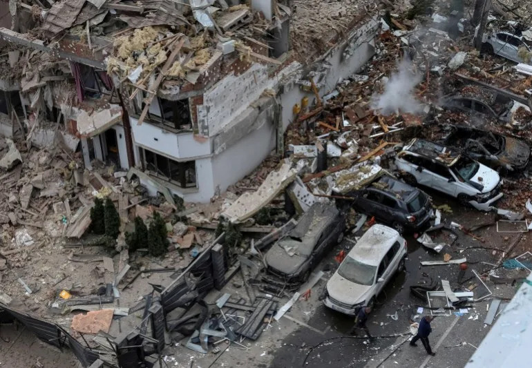 People walk next to a damaged building and vehicles in a residential neighbourhood hit during a Russian drone and missile strike, amid Russia's attack on Ukraine, on the outskirts of Kyiv, Ukraine, September 28, 2025. REUTERS/Anatolii Stepanov TPX IMAGES OF THE DAY