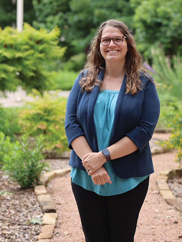 Dr. Mary Foltz, an assistant professor in the School of Civil and Environmental Engineering, is pictured in a portrait style with a garden behind her.