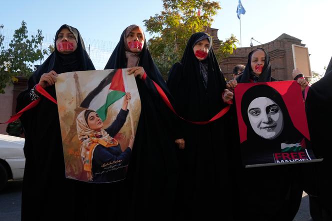 Demonstrators, mouths taped closed, hold portraits of Mahdieh Esfandiari, an Iranian national detained in France, during a protest in front of the French Embassy in Tehran to demand her release, Iran, Tuesday, October 21, 2025.
