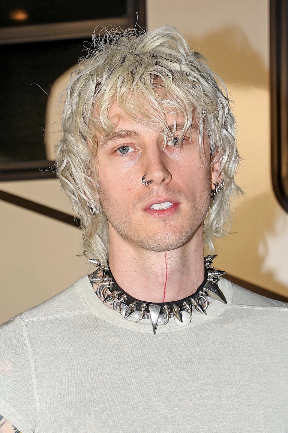 Machine Gun Kelly is wearing a choker necklace and sheer white top