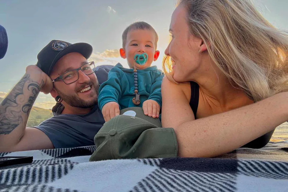 James and Georgia with their son on a picnic blanket. 