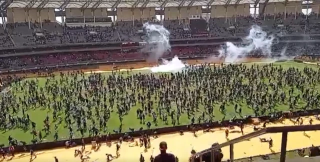 People on the pitch of the international stadium in Nairobi. Clouds of tear gas can be seen in the background of the picture