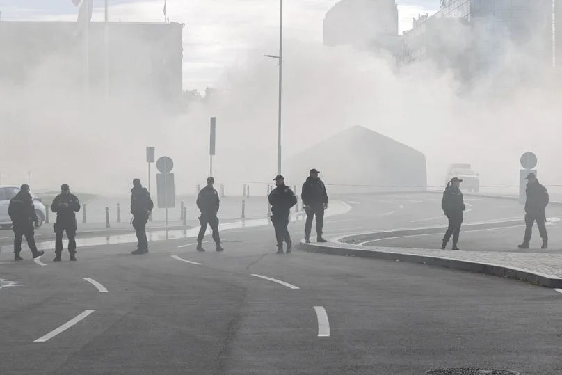 Police officers stand on a street as a fire is localized inside the government supporters' camp outside the Serbian parliament in Belgrade, Serbia, Wednesday, Oct. 22, 2025
