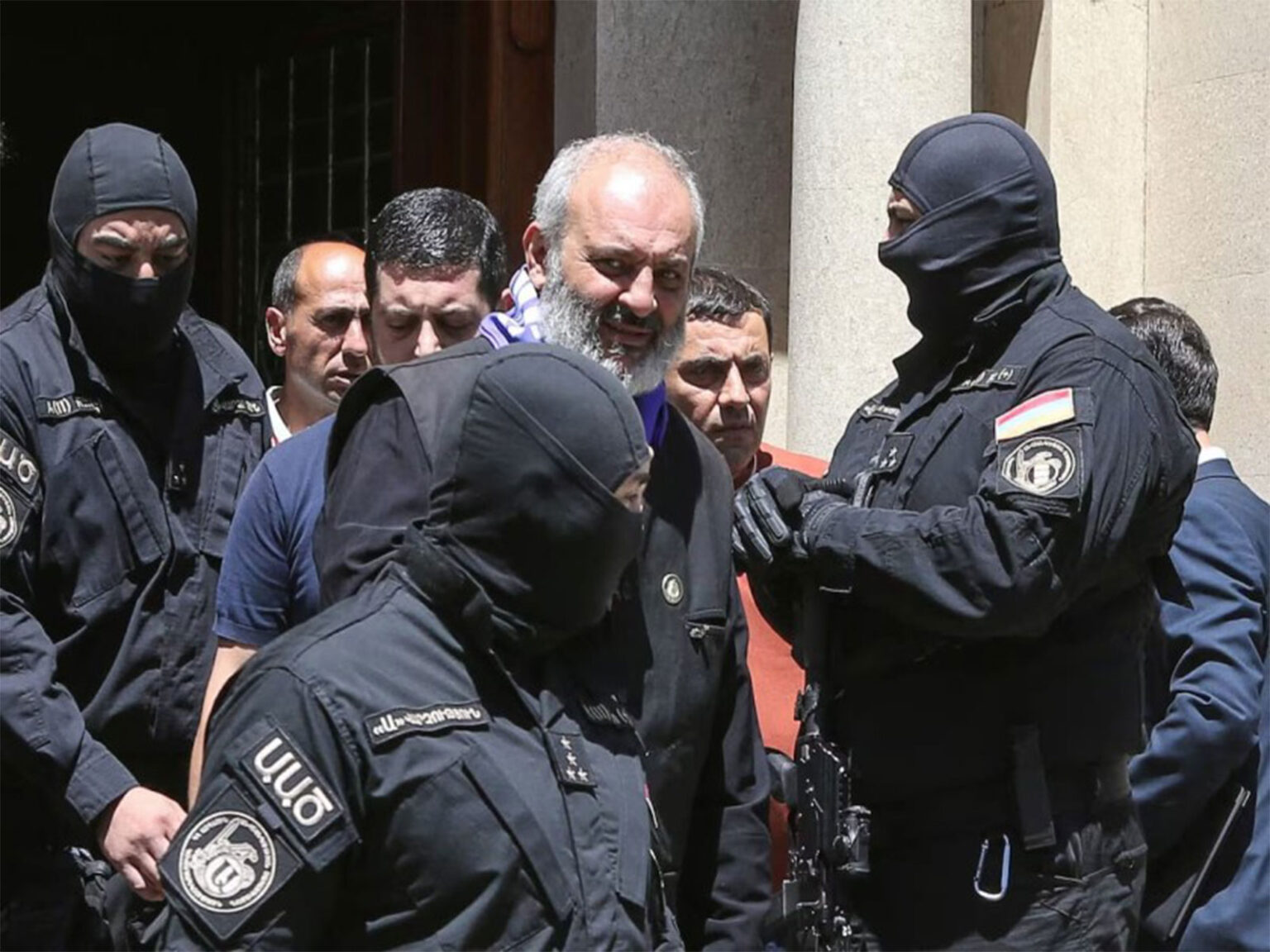 Armenian Archbishop Mikael Ajapahyan jailed for two years on coup charges amid church-government rift Armed security personnel escort a cleric under detention amid heightened tensions between Armenia’s government and the national church. (File Photo/Reuters)