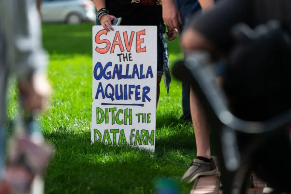 An attendee holds a sign boycotting a proposed data center at a protest in front of the Potter...