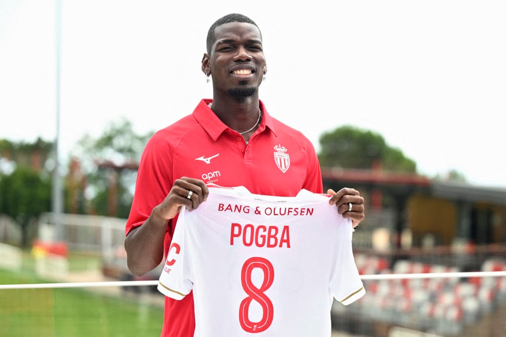 Paul Pogba poses with his new Monaco jersey while smiling.