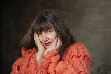 Woman in oragne jumper poses for the camera