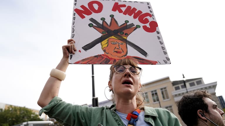 A demonstrator carries a sign as they rally at the 14th and U street corridor before marching to the national Mall during a No Kings protest in Washington
