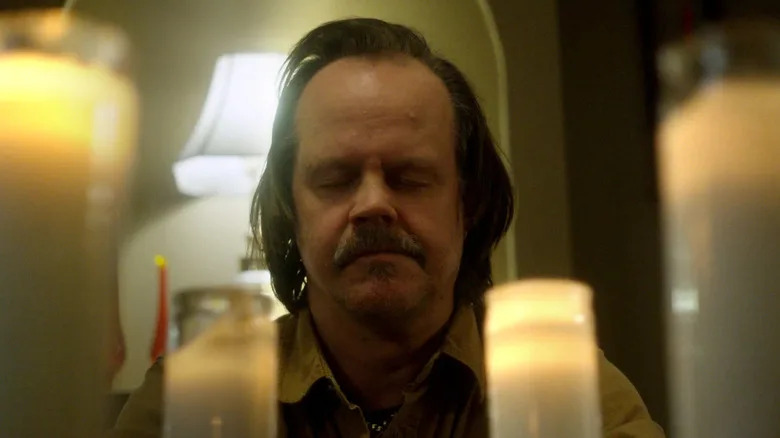 Jacob Lewis sitting at a candle altar in "We Are Still Here"