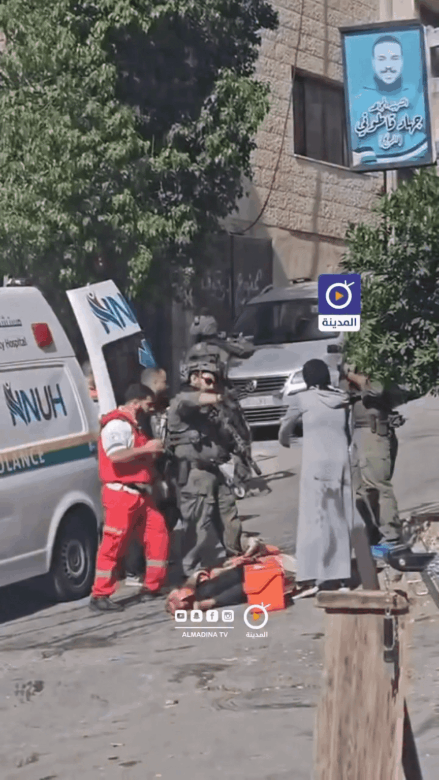 An Israeli soldier assaults a woman as she tries to prevent occupation forces from seizing her husband's body after he was shot by Israeli troops during their raid on the city of Nablus.