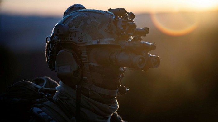 Nato spending growth lifts small French defence firms A soldier wearing camouflage gear and a helmet with night vision goggles stands in profile at sunset.