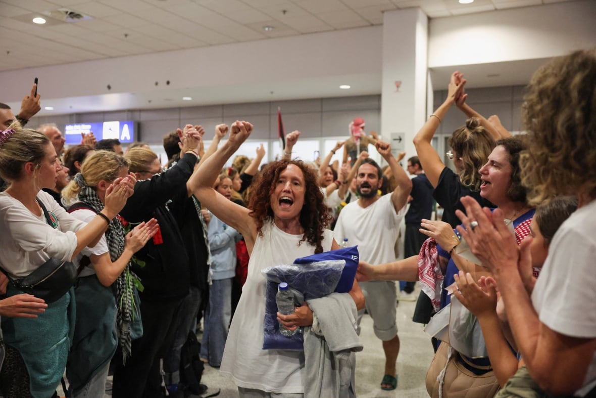People walk through a throng of cheering onlookers with their arms raised 
