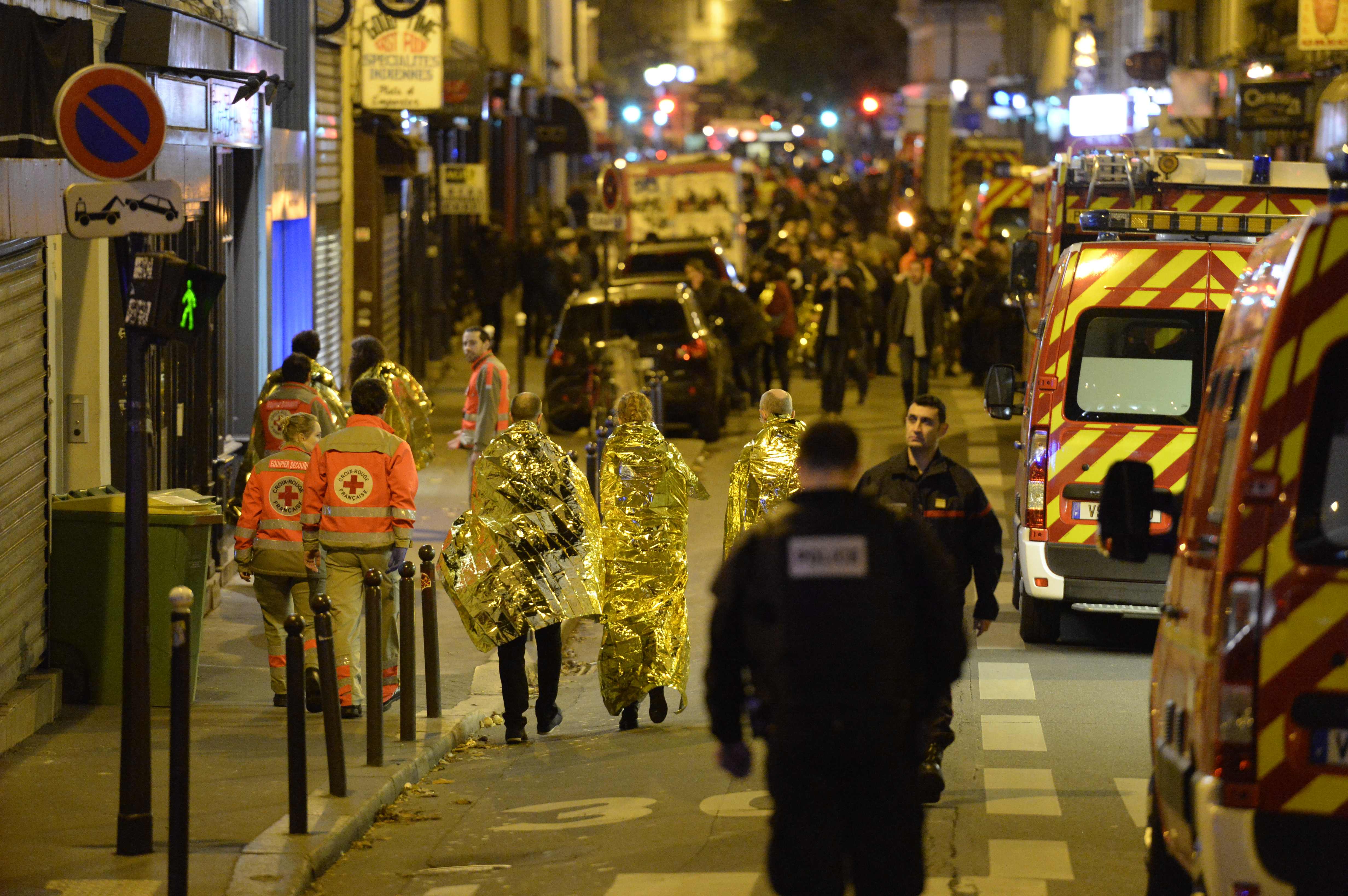 People being evacuated from rue Oberkampf near the Bataclan concert hall in central Paris, with paramedics and emergency vehicles.