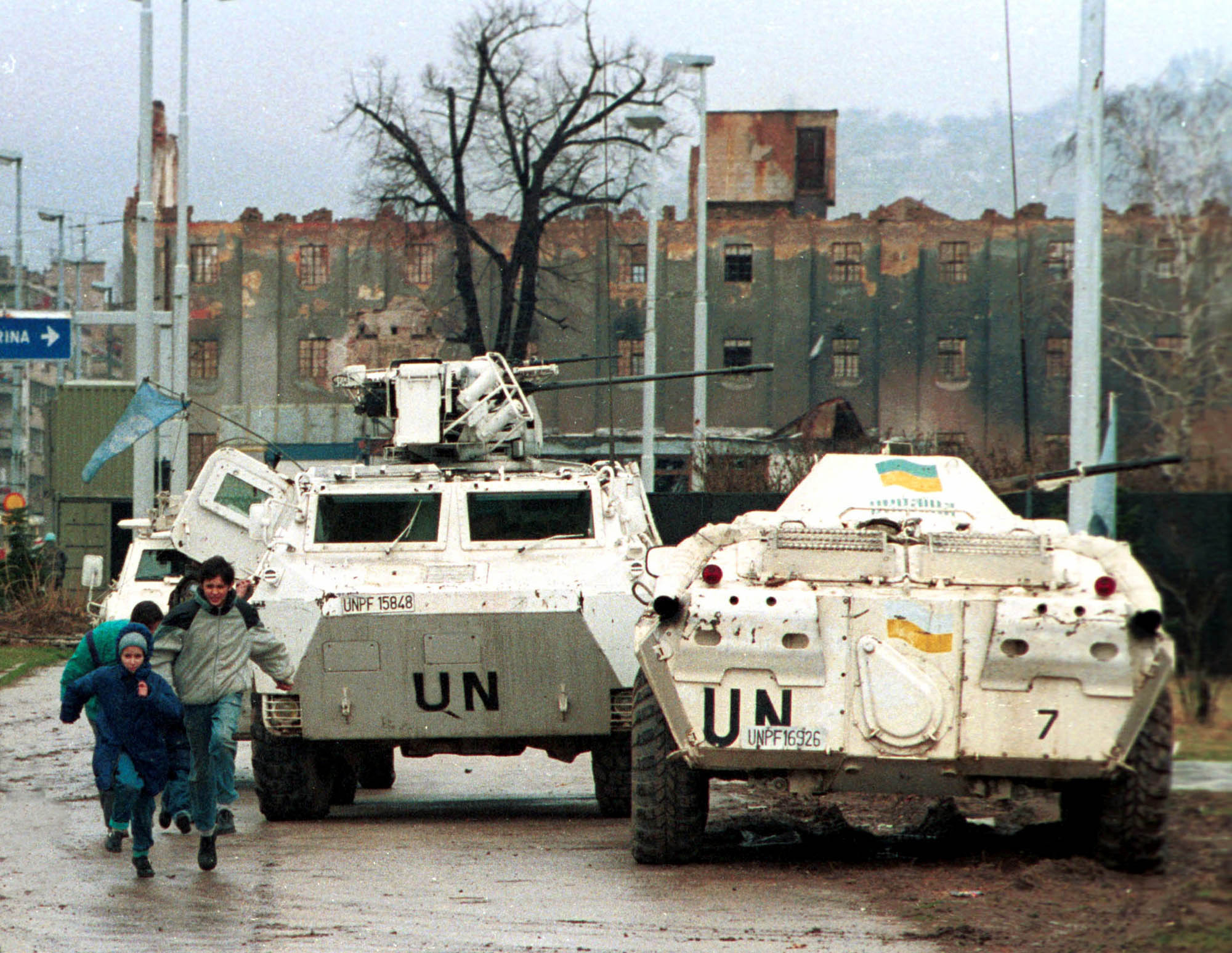 Sarajevans running past UN armored vehicles on "Sniper Alley."