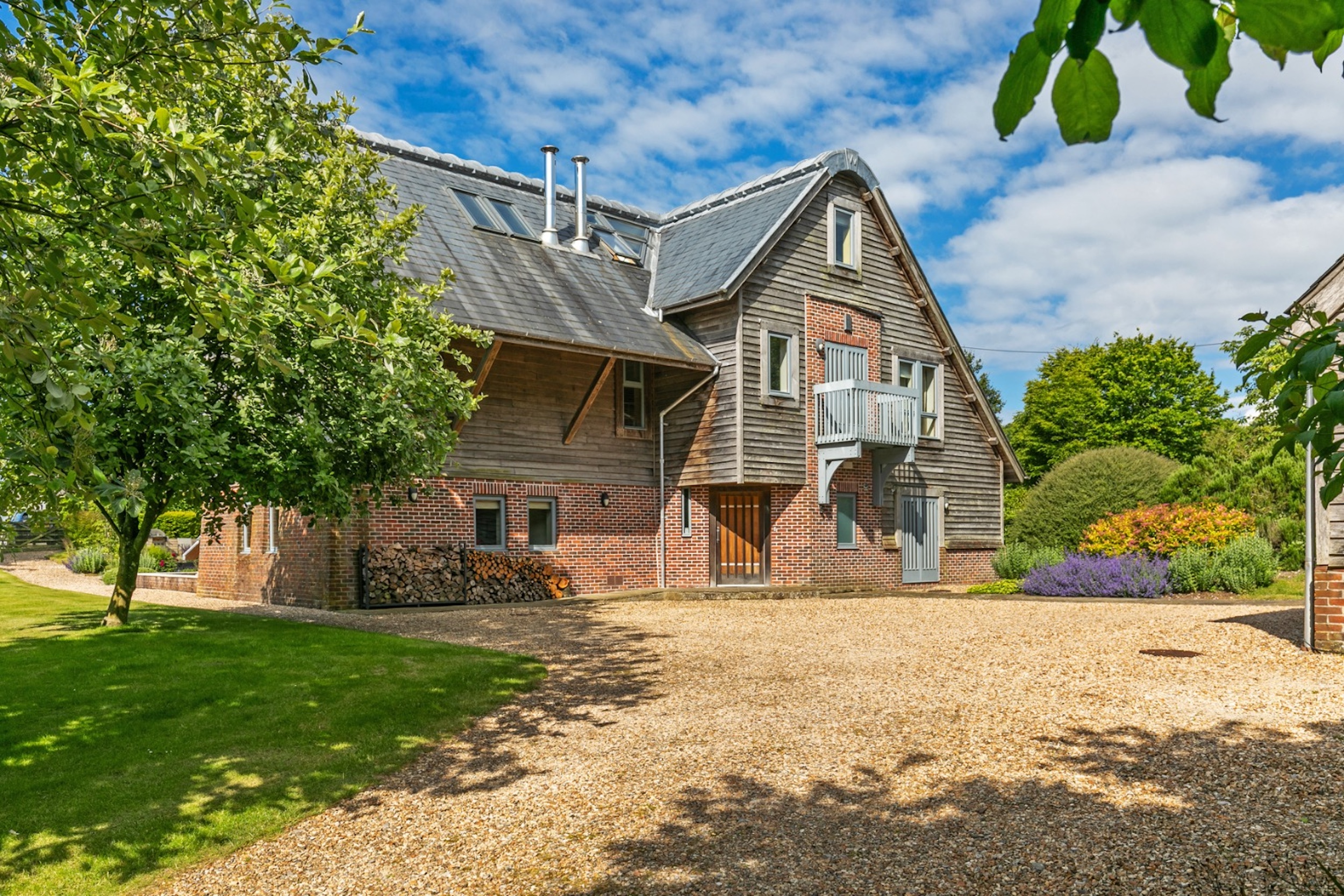 A contemporary three-story home with a gravel driveway and green lawn.