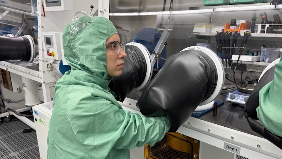 Kateryna operates a "glove box" where she puts her arms through rubber gloves to carry out a semiconductor experiment. 