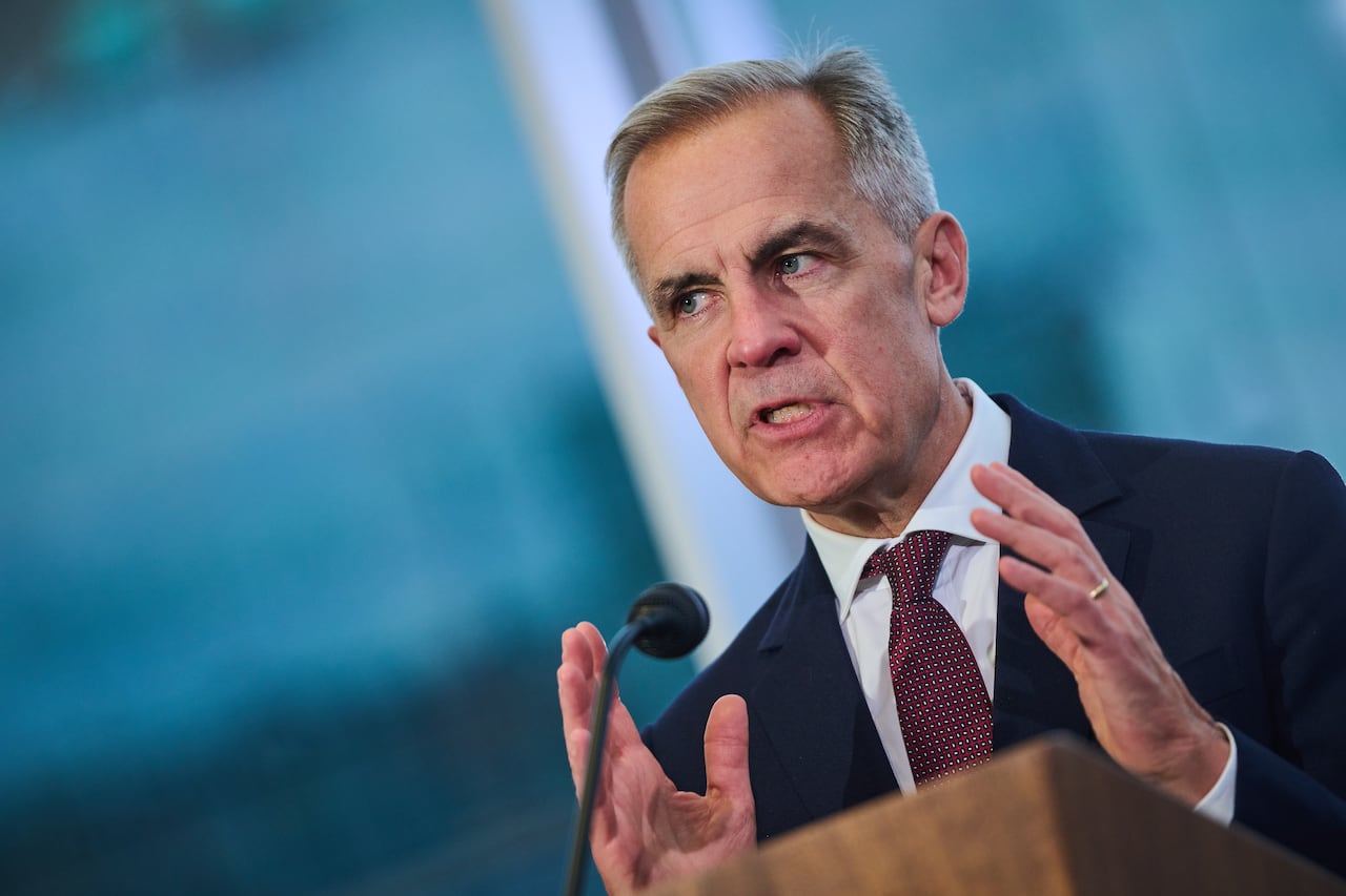 A man in a suit gestures while speaking at a podium.
