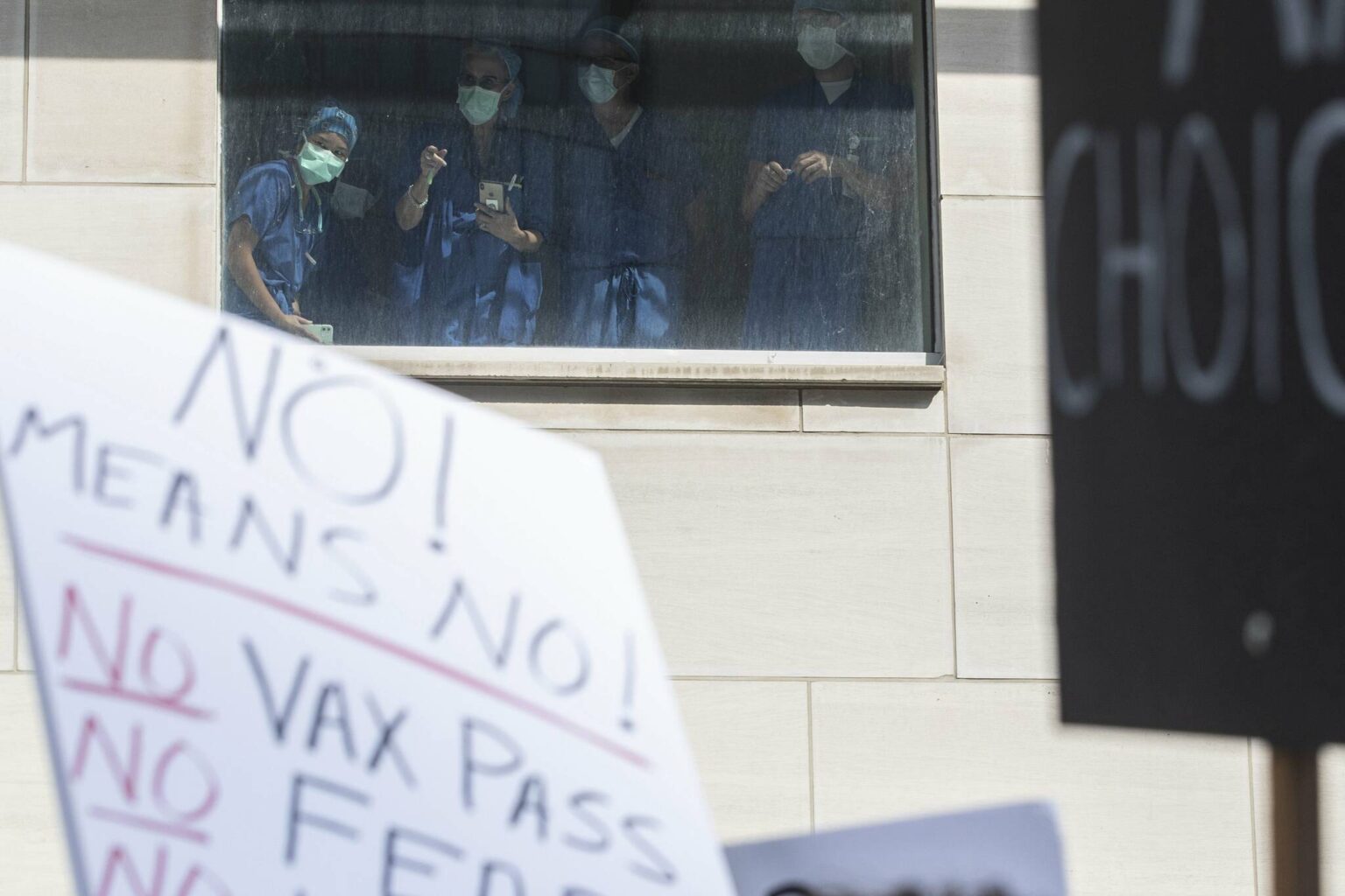 Health-care workers watch from a window as demonstrators gather outside Toronto General Hospital in September 2021 to protest against COVID-19 vaccines, COVID-19 vaccine passports and COVID-19 related restrictions. (The Canadian Press files)