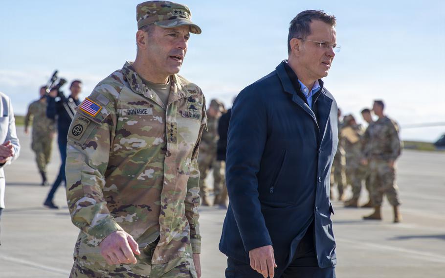 An Army general walks with a Romanian official as troops stand in the background.