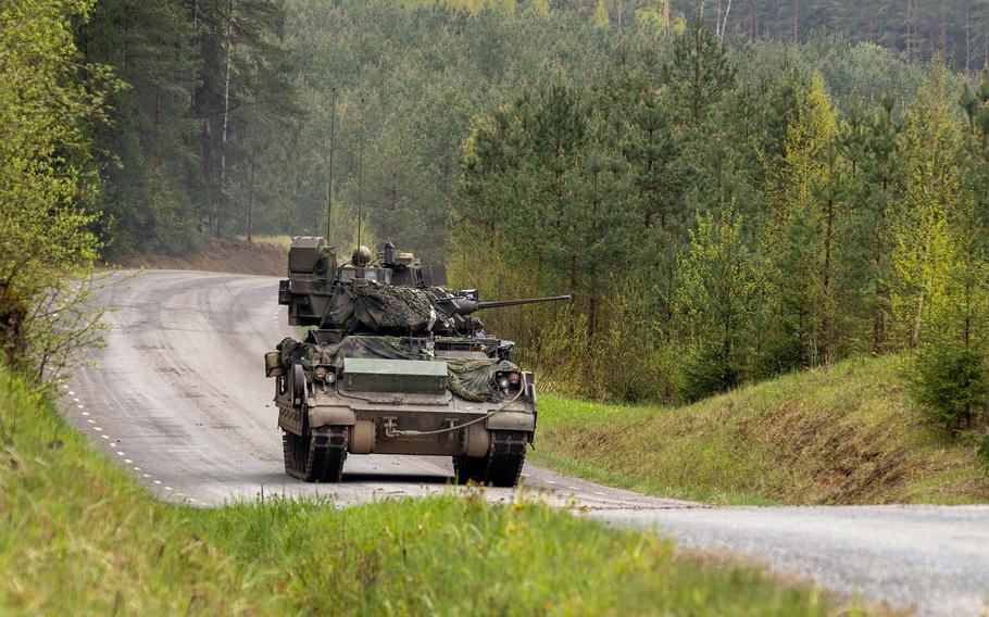 A tank on a road surrounded by greenery.