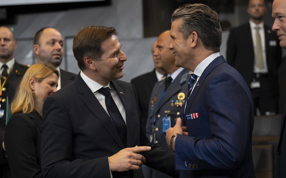 The defense minister of Estonia on the left, talking to Defense Secretary Pete Hegseth, with both of them smiling.