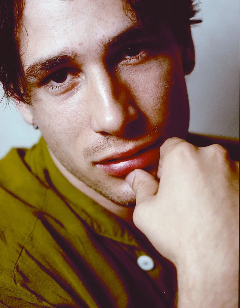 Person gazing thoughtfully, wearing a casual button-up shirt. The close-up portrait reflects a contemplative mood