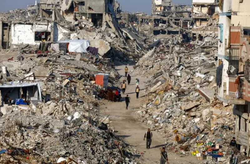 Palestinians walk among piles of rubble and damaged buildings, amid a ceasefire between Israel and Hamas, in the northern Gaza Strip November 19, 2025. (credit: REUTERS/Mahmoud Issa)