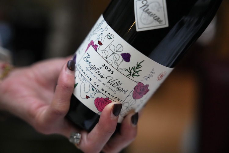 A customer pours a glass of Beaujolais Nouveau wine in a restaurant outside Paris. (Photo by AP)
