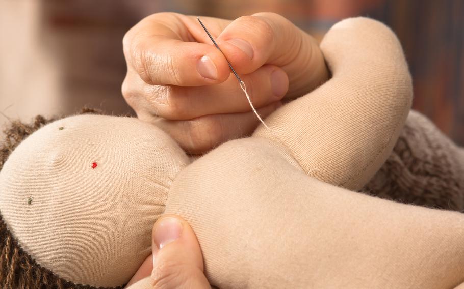 hands of woman sewing a soft doll