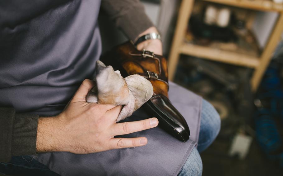 Shoemaker in workshop polishing new handmade beautiful leather shoes.