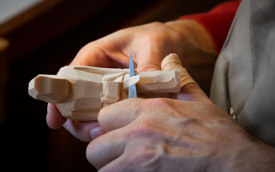 Two hands hold a carved wooden figure.