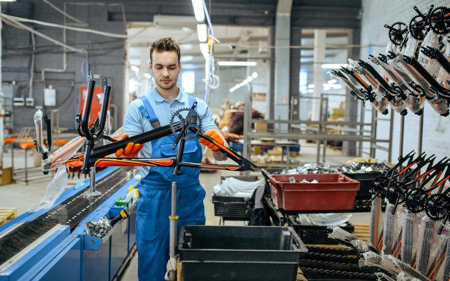 Bicycle factory, worker holds black  bike frame.